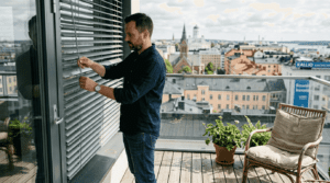 Helsinkiläismies säätää parvekkeen kaihtimia kerrostaloasunnossaan.